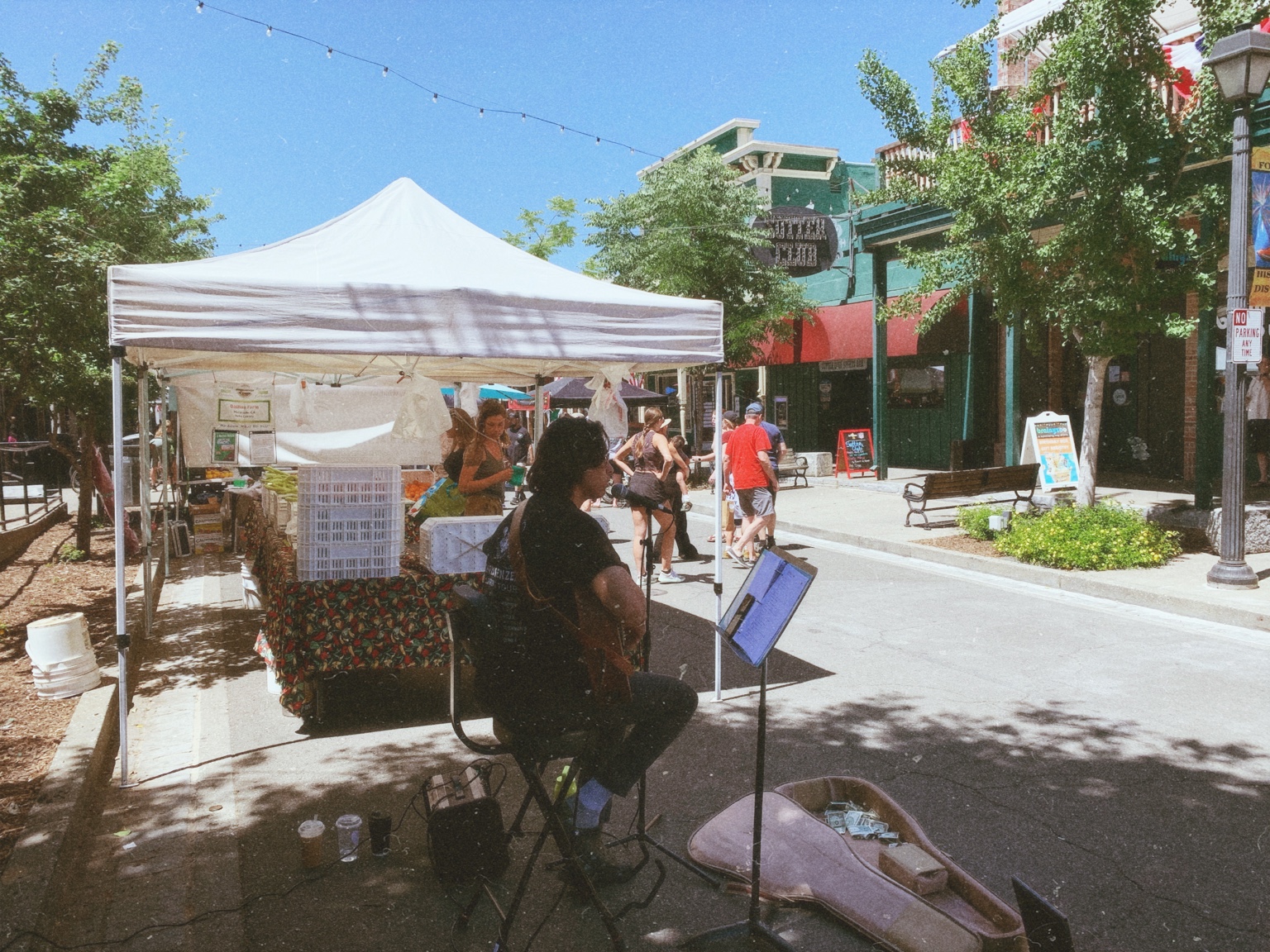 Noah performing acoustic guitar at a farmers market
